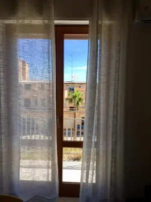 a window with white curtains and a view of a city at Casa Mia in Altavilla Milicia