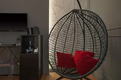 a hanging chair with red pillows in a living room at Palco Rooms&Suites in Palermo