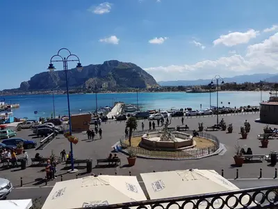 a group of people walking around a plaza next to a body of water at Mondello Vista Mare in Mondello