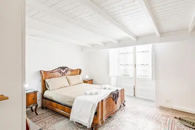 a white bedroom with a bed and a window at GuestHost - Palazzo dei Normanni Stylish Apartment in Palermo