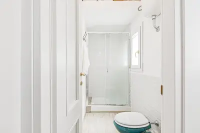 a white bathroom with a toilet and a shower at GuestHost - Palazzo dei Normanni Stylish Apartment in Palermo