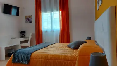 a bedroom with an orange bed and a window at La Suite Di Segesta in Calatafimi