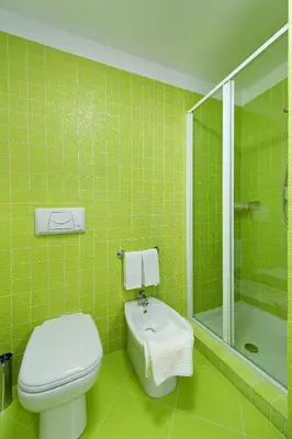a green tiled bathroom with a toilet and a shower at Le Camere del Crimiso in Castellammare del Golfo