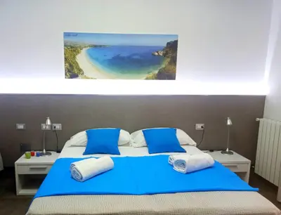 a bedroom with a blue bed with a view of a beach at Le Camere del Crimiso in Castellammare del Golfo