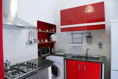 a kitchen with red cabinets and a washing machine at Bahlara Case Vacanza in Palermo