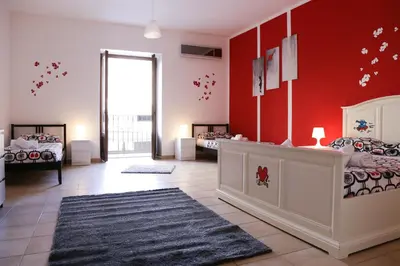 a room with two beds and a red wall at Bahlara Case Vacanza in Palermo