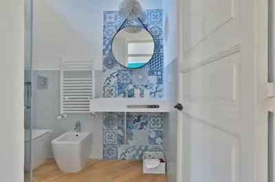 a bathroom with blue and white tiles and a mirror at Storie di Palermo in Palermo