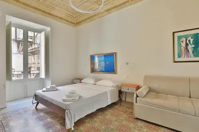 a white bedroom with a bed and a couch at Storie di Palermo in Palermo
