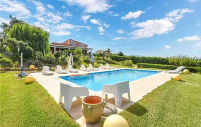 a swimming pool with white chairs and a house at Villa Musasealdoge in Partinico
