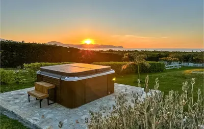 a grill with a bench and the sunset in the background at Villa Musasealdoge in Partinico
