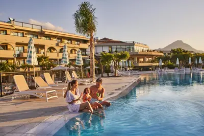 a family sitting in the pool at a resort at The Signature Level at Grand Palladium Sicilia Resort & Spa in Campofelice di Roccella