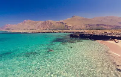 a person swimming in the ocean next to a beach at Bed & Breakfast Tiziana in Castellammare del Golfo