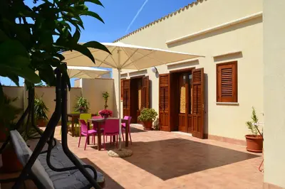 a patio with a table and chairs and an umbrella at La Giara San Vito Lo Capo in Castelluzzo