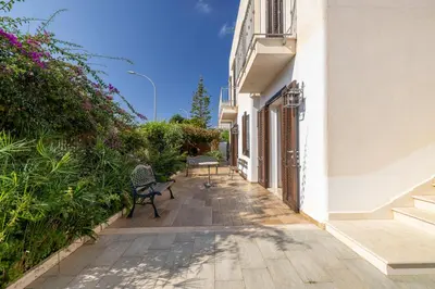 a walkway between a building with two benches at Casa Vacanza Azzurra in San Vito lo Capo