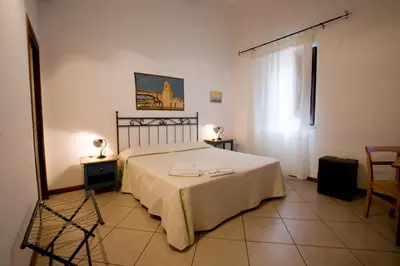 a bedroom with a bed and two chairs and a window at Aziyz Camere in Castellammare del Golfo