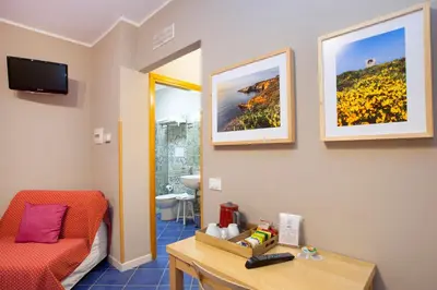 a room with a bed and a table and a television at TerraSole Bakery B&B in Terrasini