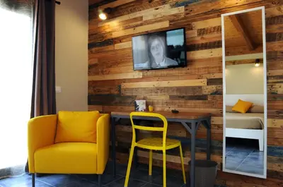 a room with a yellow chair and a tv on a wooden wall at TerraSole Bakery B&B in Terrasini