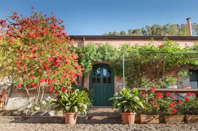a house with red flowers and a green door at Masseria Pernice in Monreale