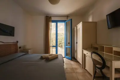 a bedroom with a bed and a sliding glass door at Hotel Tannure in San Vito lo Capo