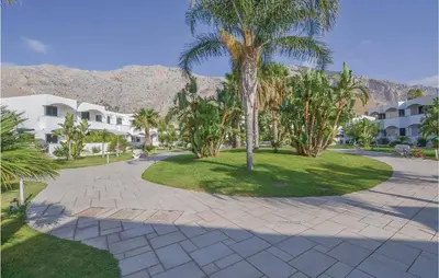 a park with palm trees and buildings and mountains at Appartamento Darling in Isola delle Femmine