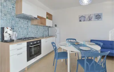 a kitchen with a table and blue chairs in a kitchen at Appartamento Darling in Isola delle Femmine