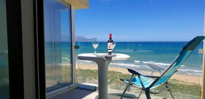 a table with a bottle of wine and a chair on the beach at La Dimora di Venere in Alcamo