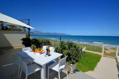 a white table and chairs on a balcony with the ocean at La Dimora di Venere in Alcamo