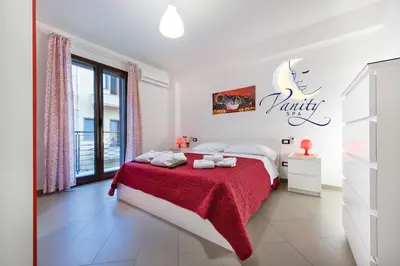 a white bedroom with a bed with a red blanket at Vanity SPA in Balestrate