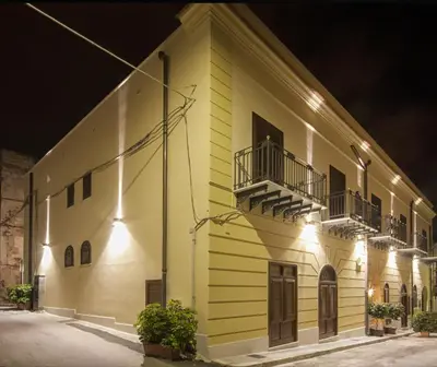 a yellow building with two balconies on it at night at Residenza Le Zagare in Castellammare del Golfo