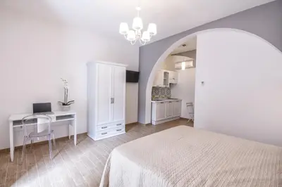 a white bedroom with a bed and a desk and a computer at Residenza Le Zagare in Castellammare del Golfo