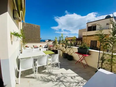 a patio with white chairs and tables on a balcony at Casa Helios in Castellammare del Golfo