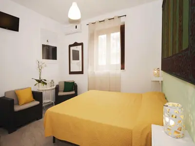 a bedroom with a yellow bed and two chairs at Casa Helios in Castellammare del Golfo
