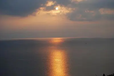 a sunset over the ocean with the sun reflecting on the water at Blue Island Villa Caterina in Casteldaccia