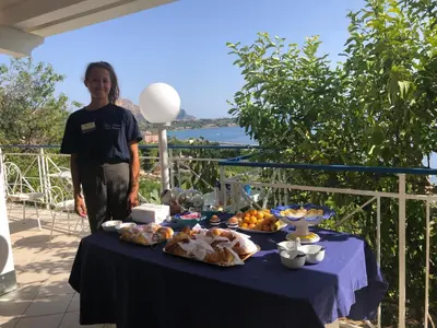 a woman standing next to a table with food on it at Blue Island Villa Caterina in Casteldaccia