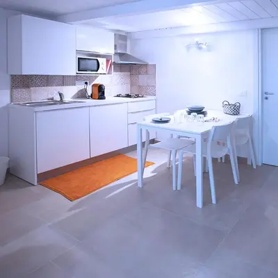 a white kitchen with a white table and chairs at SpasimoH-3 in Palermo