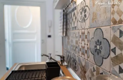 a kitchen with a sink and a tile wall at Casa Novelli Apartments in Monreale
