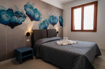 a bedroom with a bed and a wall with blue flowers at Residence Marinella in San Vito lo Capo