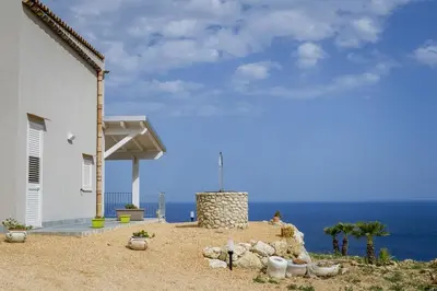 a table on a balcony with a view of the ocean at Villa Rosaria vicino la Riserva dello Zingaro in Scopello