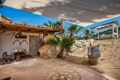 an outdoor patio with a table and a barrel at APT Villa Anna e APT Cantina Vito vicinissimi alla Riserva dello Zingaro in Scopello
