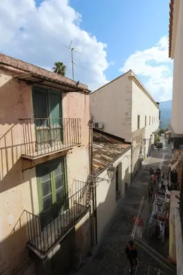 an alley with buildings and a man walking down it at Torre's Camere & caffè in Monreale