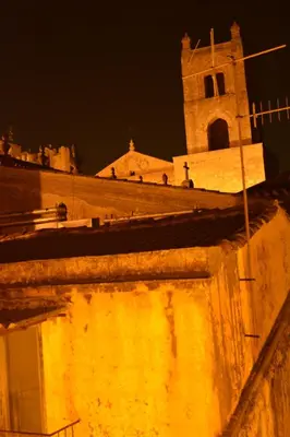 a building with a clock tower at night at Torre's Camere & caffè in Monreale