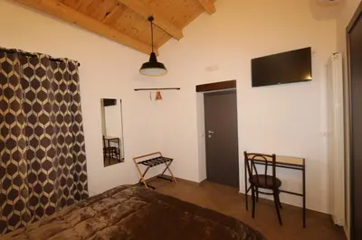 a bedroom with a bed and two chairs and a tv at Torre's Camere & caffè in Monreale