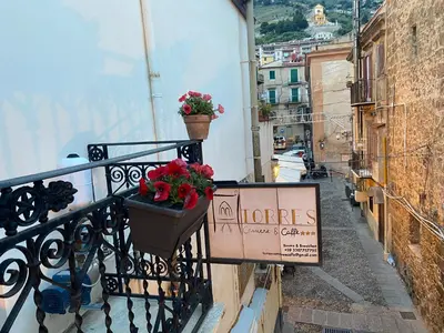 a balcony with flowers and a sign on it at Torre's Camere & caffè in Monreale