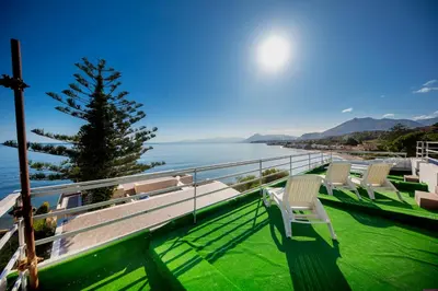 a row of chairs on a balcony overlooking the water at Villa Francesca 30 Pax by Ville in Palermo in Casteldaccia