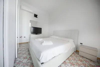 a white bedroom with a white bed and a tv at Appartamento 16 Pax in Villa Francesca by Ville in Palermo in Casteldaccia