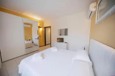 a bedroom with a white bed and a bathroom at Appartamento 23 Pax in Villa Francesca by Ville in Palermo in Casteldaccia