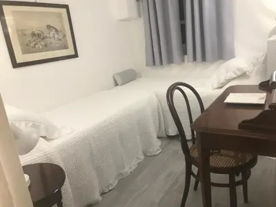 a small white bedroom with a desk and a bed at Home 3L in Palermo