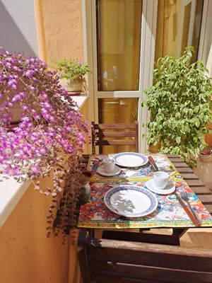 a table with plates and cups on a balcony with flowers at 