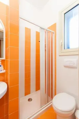 an orange and white bathroom with a toilet and a shower at B&B 