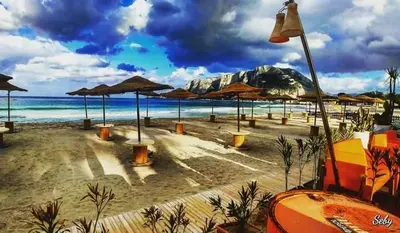 a beach with umbrellas and chairs and the ocean at Hostel Centro BASEMENT in Palermo